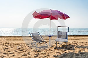 Sunbeds and parasol beach umbrella at the sunny beach in Italy