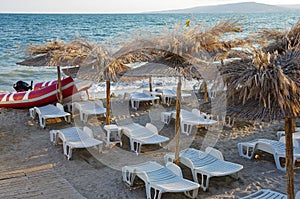 Sunbeds and rattan parasols on sandy beach