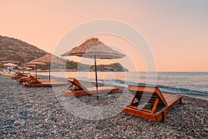 Sunbeds and sun umbrellas await vacationers on the shingle beach at Ovabuku beach on the Datca Peninsula in Turkey. photo