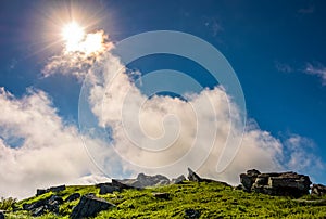 Sunburst on a blue sky with clouds over the mountains