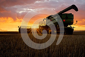 Sunburst through combine at sunset on the prairies in Saskatchewan, Canada photo