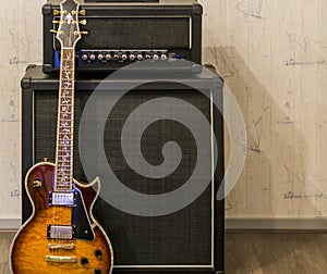 Sunburst electric guitar standing in front of a amplifier and sound effect box, professional music equipment