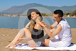 Suncare couple on a summer beach vacation have good skincare with high spf sunblock. Couple applying suncream. Handsome man