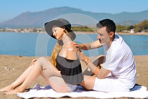 Suncare couple on a summer beach vacation have good skincare with high spf sunblock. Couple applying suncream. Handsome man