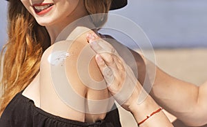 Suncare couple on a summer beach vacation have good skincare with high spf sunblock. Couple applying suncream.