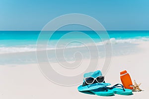 Suncream bottles, goggles, starfish and sunglasses on white sand beach background ocean