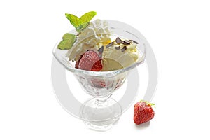 Sundae dessert with ice cream, fresh strawberries, whipped cream and peppermint garnish in a glass goblet, isolated with shadows