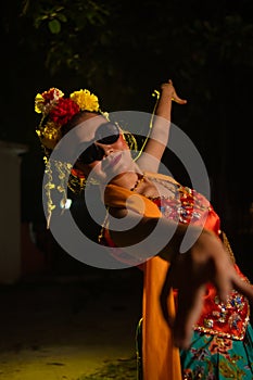 a Sundanese dancer dances very agilely while wearing sunglasses on her face