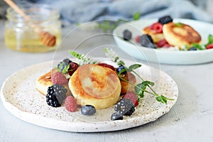 Sunday breakfast with cheesecake, honey, fresh berries and mint. Cottage cheese pancakes or curd fritters decorated honey