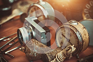 Retro alarm clocks, camera and rusty plumb bob on countertop in sunday flea market.