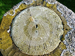 Sundial covered with lichen in graveyard