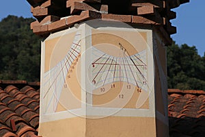 sundial with hour numbers on the chimney of a house facing south