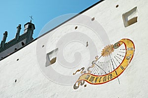 Sundial on white castle wall at sunny day