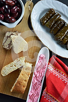 Sunflower halva and lagana bread on cutting board,olive dish with taramosalata,kalamon olives on bowl and stuffed grape leaves