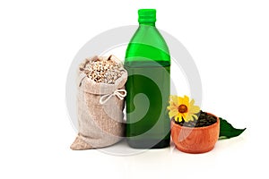 Sunflower oil in glass bottle, sunflower seeds in sack and rustic wooden bowl with flower and leaves on white background
