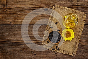 Sunflower oil in glass cruet with flower head and seeds in wooden bowl