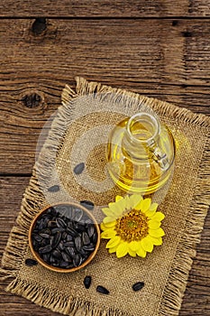 Sunflower oil in glass cruet with flower head and seeds in wooden bowl