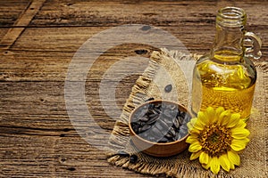 Sunflower oil in glass cruet with flower head and seeds in wooden bowl