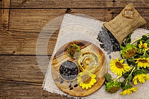 Sunflower oil in glass cruet with flower head and seeds in wooden bowl