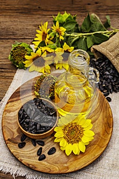 Sunflower oil in glass cruet with flower head and seeds in wooden bowl