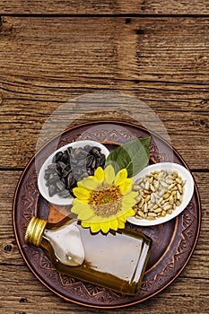 Sunflower oil in glass cruet with flower head and seeds in wooden bowl