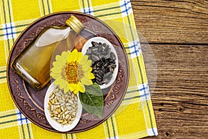 Sunflower oil in glass cruet with flower head and seeds in wooden bowl