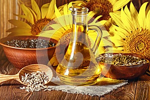 The sunflower oil in glass cruet with flowers of sunflower Helianthus annuus and seeds in wooden bowls against the background of