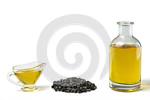 Sunflower oil in a glass gravy boat, in a bottle, and a handful of sunflower seeds isolated on a white background