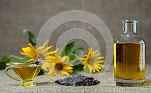 Sunflower oil in a glass gravy boat and in a bottle, and a handful of sunflower seeds