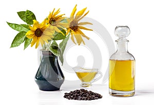 Sunflower oil in a glass gravy boat and in a bottle, handful of sunflower seeds and a sunflower in a vase