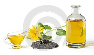 Sunflower oil in a glass gravy boat and in a bottle, handful of sunflower seeds and sunflowers.