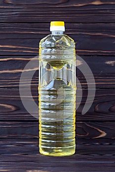 Sunflower oil in a plastic bottle on dark wooden boards, yellow salad-oil, transparent packaging. Healthy organic product. Food