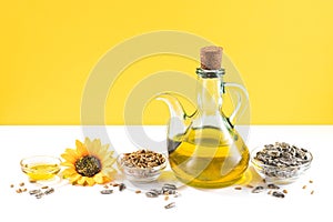 Sunflower oil and sunflower seeds on white and yellow background with copyspace