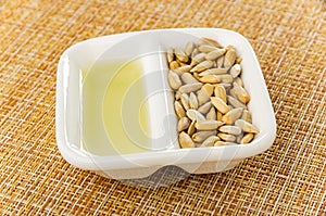 Sunflower oil, sunflower seeds in partitioned bowl on brown mat