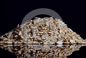 Sunflower peeled seeds on a black glass background