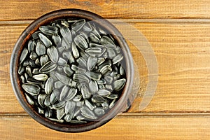 Sunflower seeds in the small bowl on the wooden background