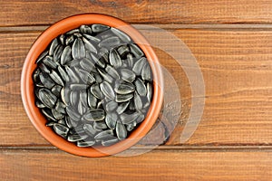 Sunflower seeds in the small bowl on the wooden background