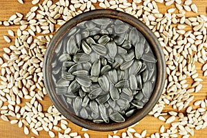 Sunflower seeds in the small bowl on the wooden background