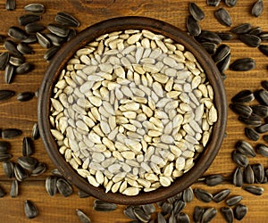 Sunflower seeds in the small bowl on the wooden background