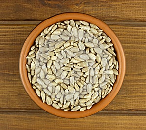 Sunflower seeds in the small bowl on the wooden background