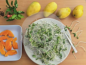 Sunflower sprouts, papaya slices on plate