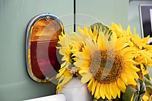 Sunflowers next to the rear brake lights on a vintage car