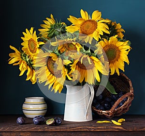 Sunflowers and plums. Still life with flowers and berries.