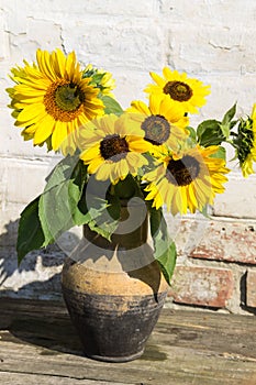 Sunflowers in vintage clay jug on wooden table