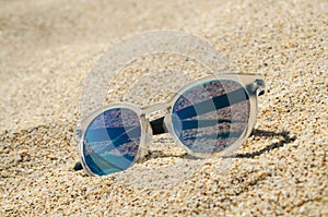 Sunglasses on the beach. Multi colored stylish model with transparent frame and blue lenses. Vacation concept.