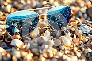 Sunglasses on the beach with sea reflection in them