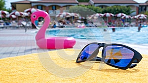 Sunglasses beach summer vacation background. Beach pool equipment with travel sunglasses on yellow holiday towel