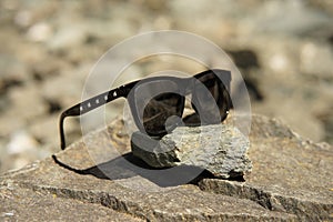 Sunglasses black with silver rectangled rivets on glasses temples an rocks reflecting sun