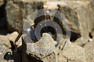 Sunglasses black with silver rectangled rivets on glasses temples an rocks reflecting sun