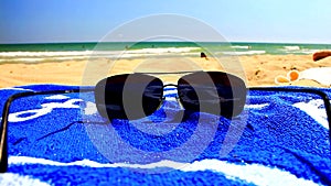 Sunglasses and blue towel on sandy beach